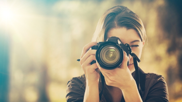 Portrait of a photographer covering her face with camera.